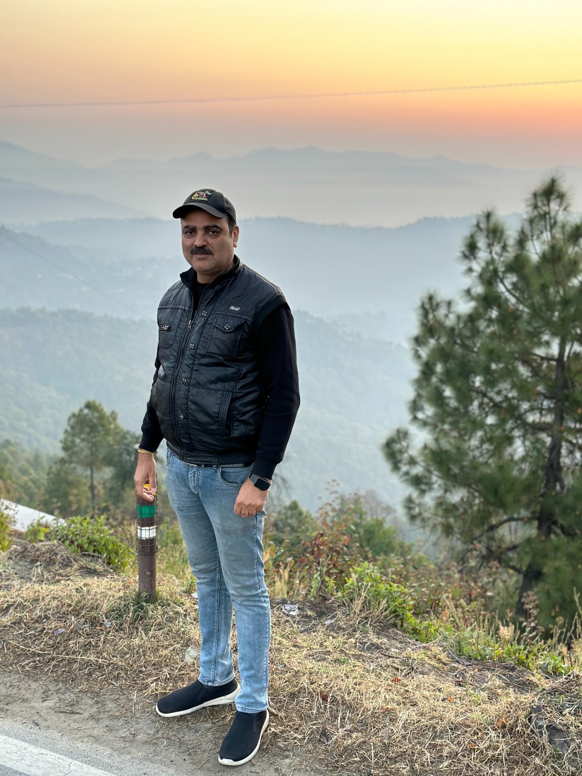 Gaurav Ghulati standing near a mountain overlook at sunset.