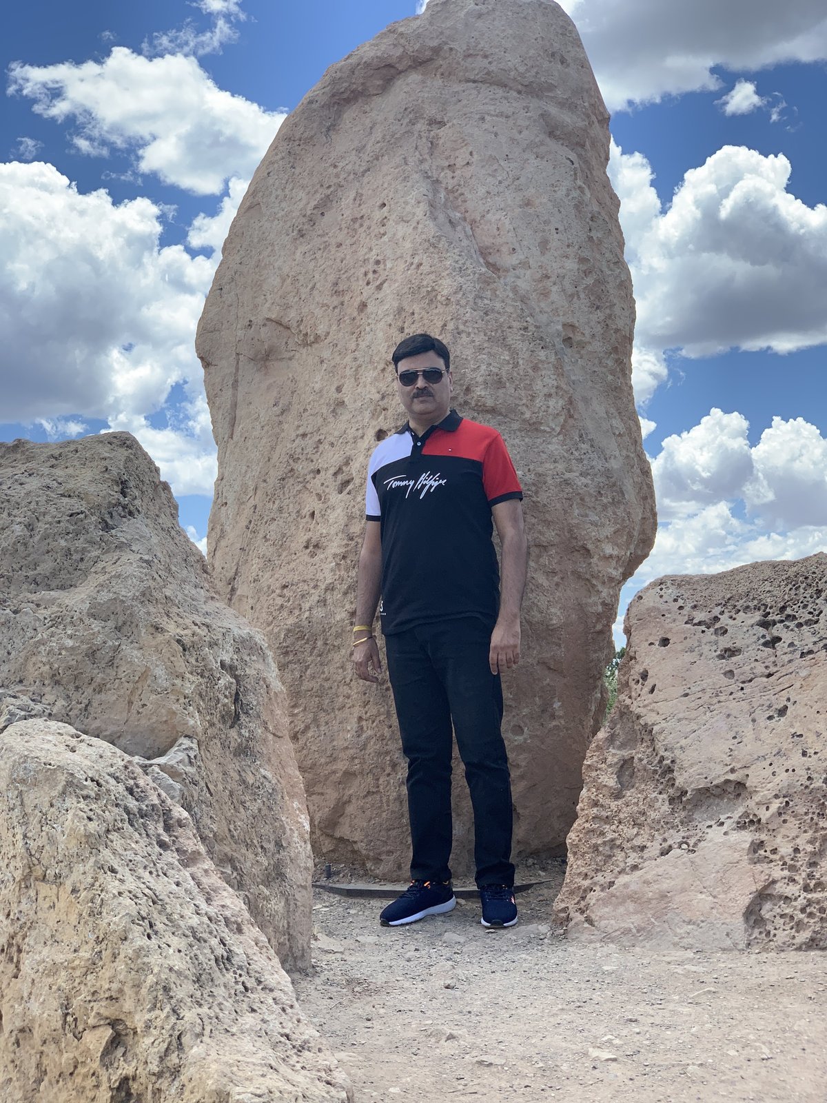 Gaurav Ghulati standing beside a tall desert rock formation.